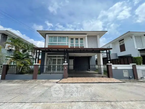 Modern two-story house with sleek design and spacious driveway in a suburban neighborhood.