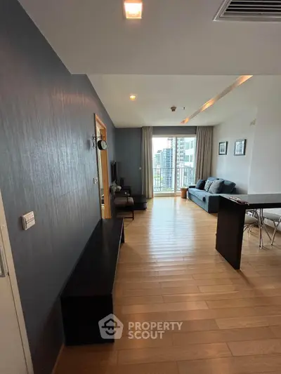 Spacious modern living room with wooden flooring and city view balcony.