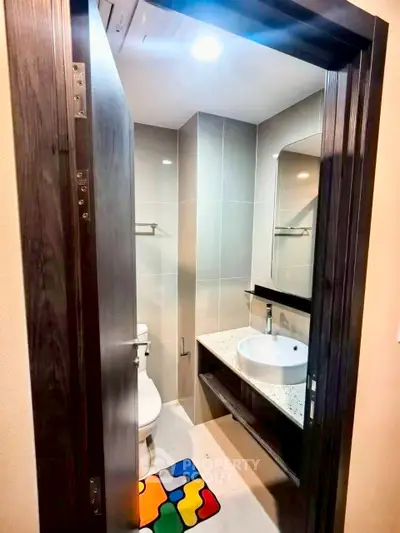 Modern compact bathroom with sleek fixtures and colorful mat