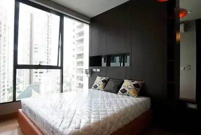 Modern bedroom with large windows offering stunning city views in a high-rise apartment.