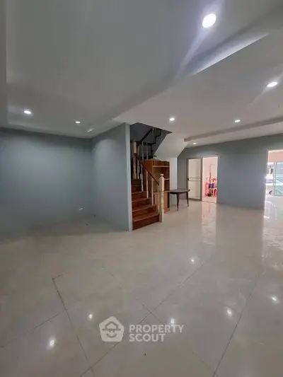 Spacious modern living room with elegant staircase and recessed lighting