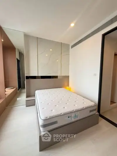 Modern bedroom with sleek design and large mirrors enhancing space and light.