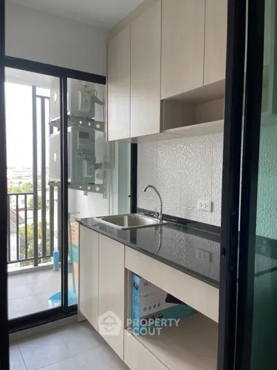 Modern kitchen with sleek cabinetry and balcony view, perfect for urban living.
