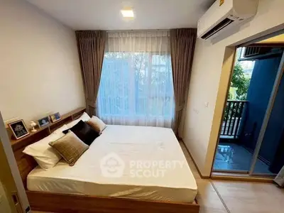 Cozy bedroom with large window and balcony access, featuring modern decor and air conditioning.