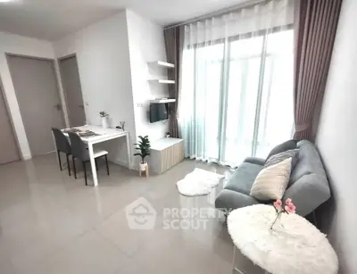 Modern living room with cozy sofa and dining area, bright natural light through large windows.