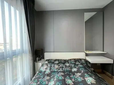 Modern bedroom with floral bedding and large window offering natural light.