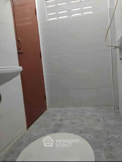 Compact bathroom with tiled walls and floor, featuring a simple design and minimal fixtures.