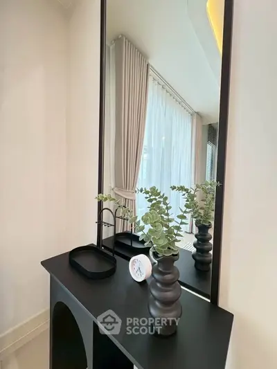 Elegant interior with modern decor and large window draped with sheer curtains, enhancing natural light.