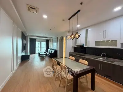 Spacious open-layout living room and kitchen with modern furnishings and elegant lighting.