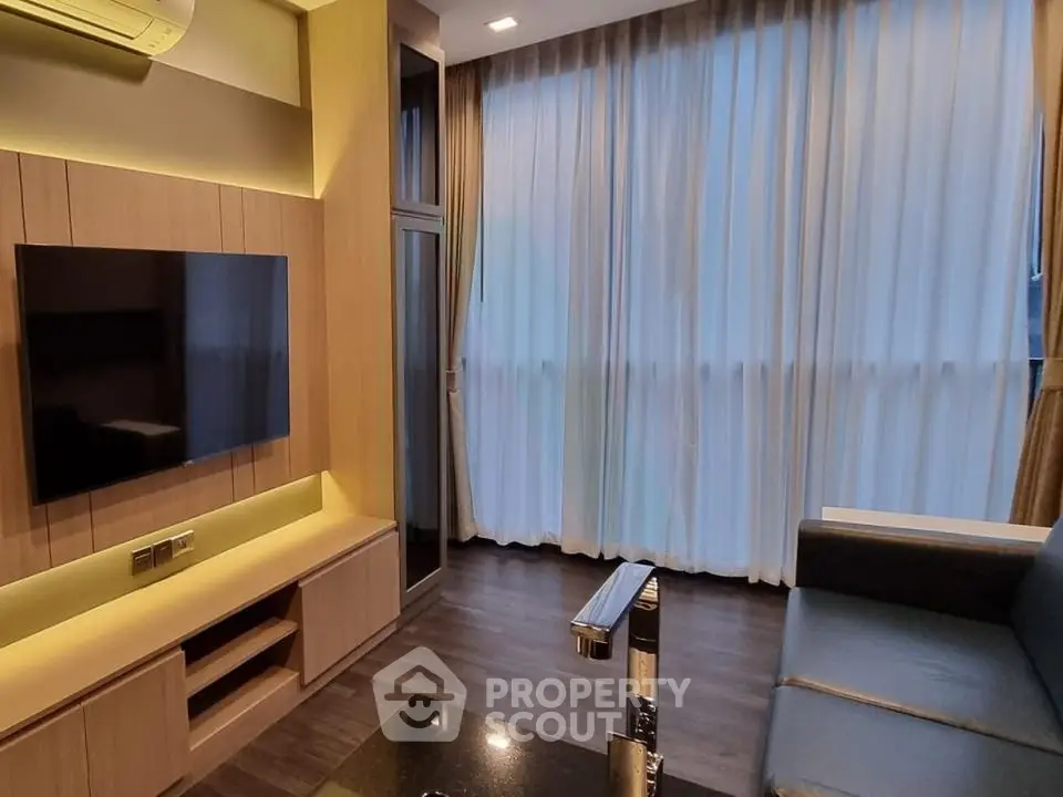 Modern living room with sleek design, large window, and wall-mounted TV in a cozy apartment.