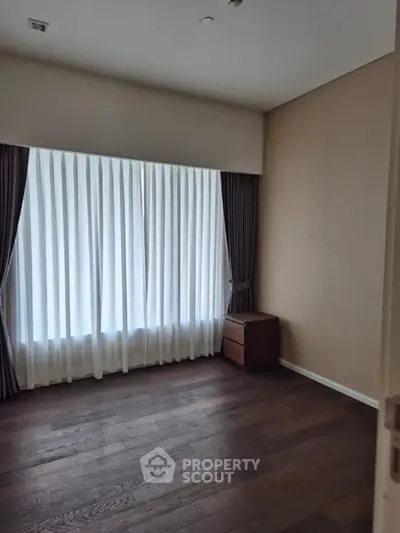Spacious empty room with elegant curtains and wooden flooring