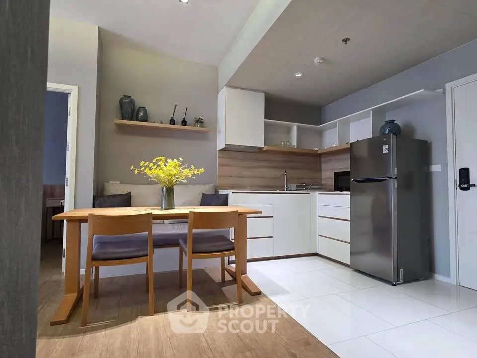 Modern kitchen with dining area, featuring sleek cabinetry and stainless steel fridge.