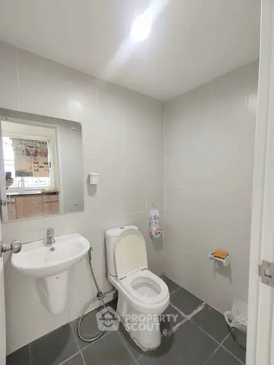 Modern bathroom with sleek fixtures and neutral tiles, featuring a toilet and sink.