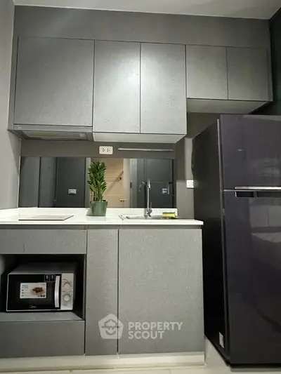 Modern kitchen with sleek cabinets and appliances, featuring a microwave and refrigerator.