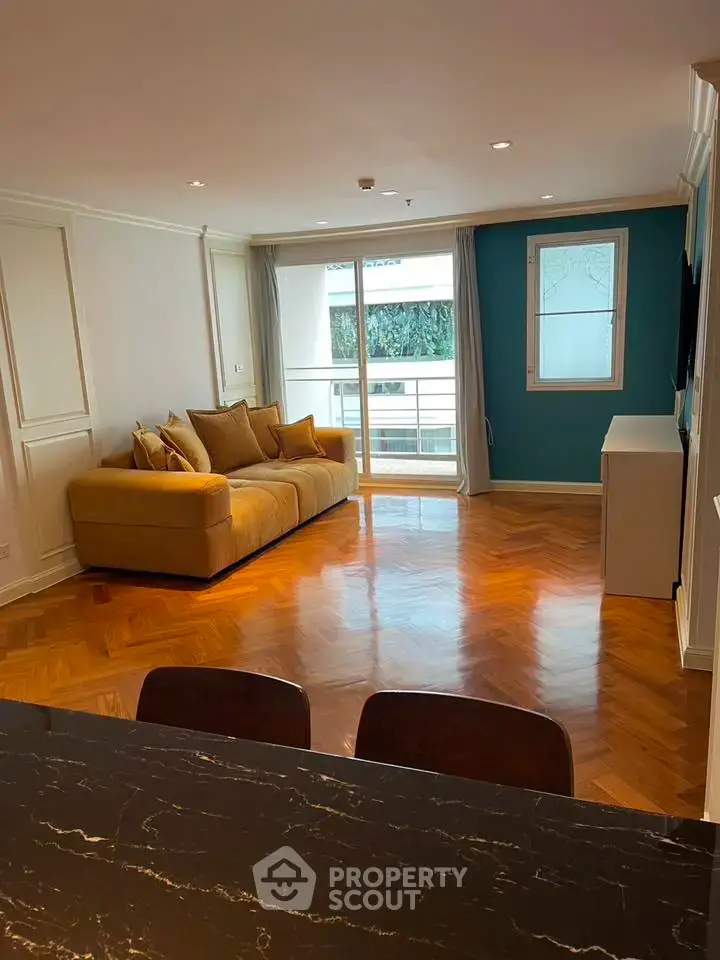 Spacious living room with elegant parquet flooring and cozy sofa, featuring a bright balcony view.