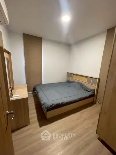 Cozy minimalist bedroom with wooden flooring and modern furnishings.