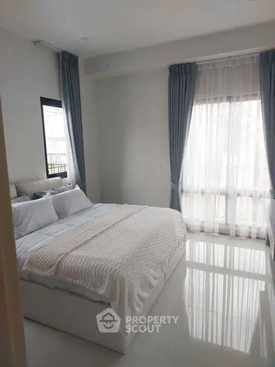Bright and airy bedroom with large windows and elegant curtains in modern apartment.