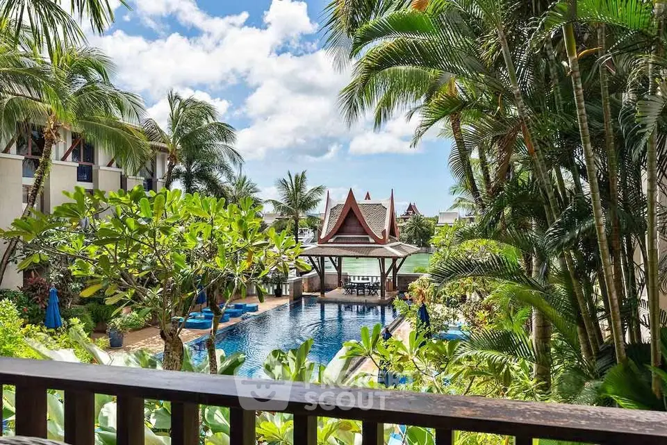Luxurious tropical resort pool surrounded by lush greenery and traditional architecture.