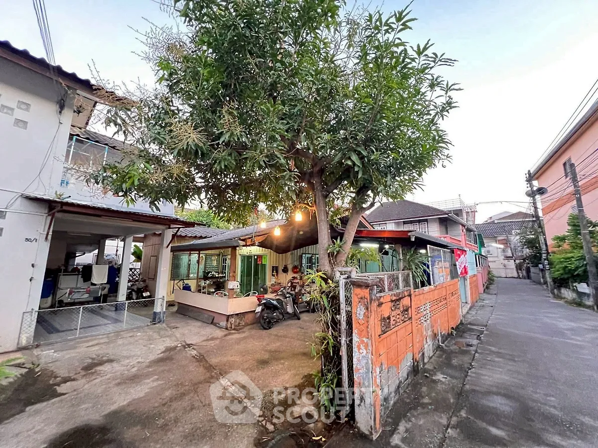 Charming urban house with spacious driveway and lush tree in front yard.