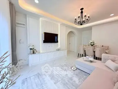 Elegant living room with chandelier and modern decor, featuring a cozy seating area and stylish dining space.