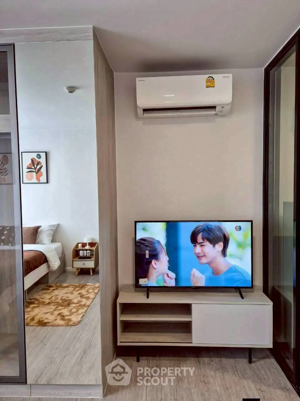 Modern living room with air conditioning and TV, adjacent to a cozy bedroom.