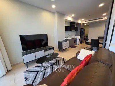 Modern living room with sleek furniture and open kitchen layout in a stylish apartment.