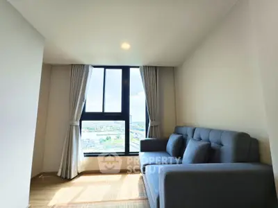 Bright living room with large window and modern sofa offering city views.