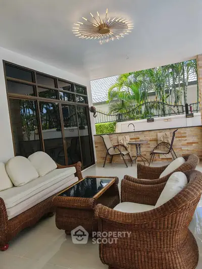 Luxurious outdoor patio with elegant wicker furniture and lush garden view, perfect for relaxation and entertaining.
