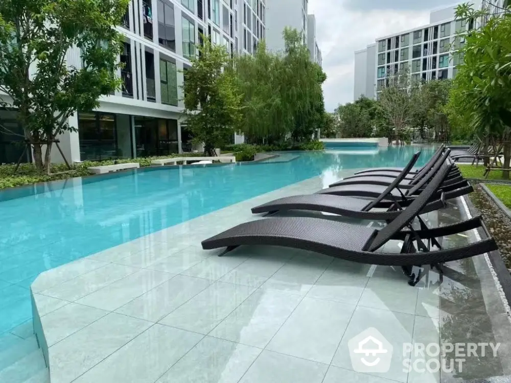 Luxurious modern apartment complex with stunning poolside view and lush greenery.