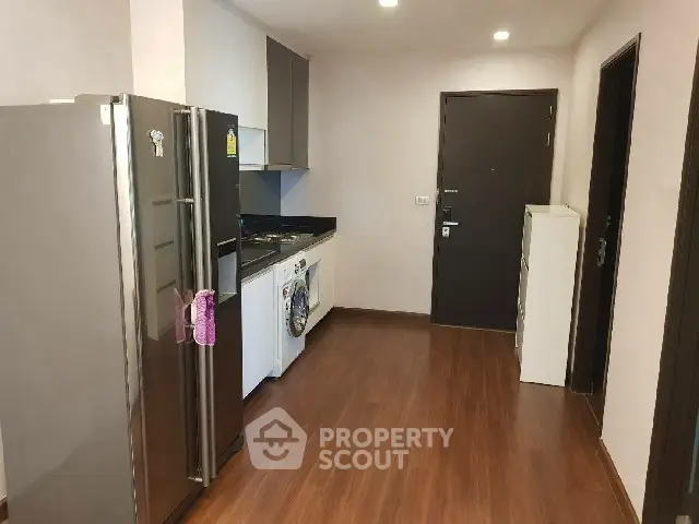 Modern kitchen with sleek appliances and wooden flooring in a contemporary apartment.