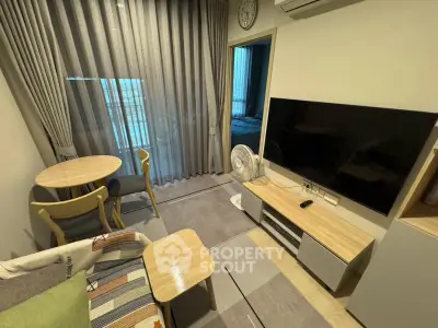 Modern living room with stylish furniture and large TV, featuring a cozy dining area and balcony access.