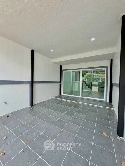 Spacious tiled patio with sliding glass doors leading to a modern interior, perfect for outdoor relaxation.