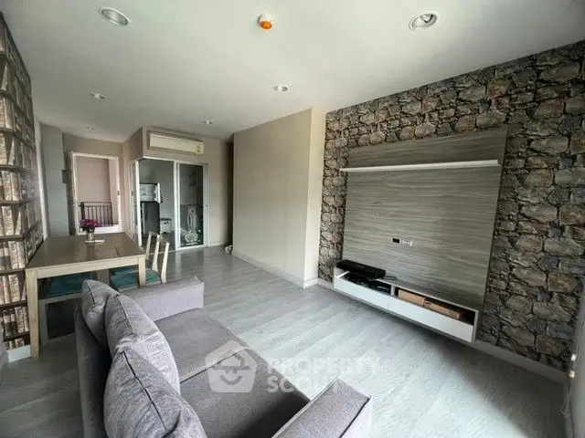 Modern living room with stone accent wall and sleek furniture in open layout apartment.