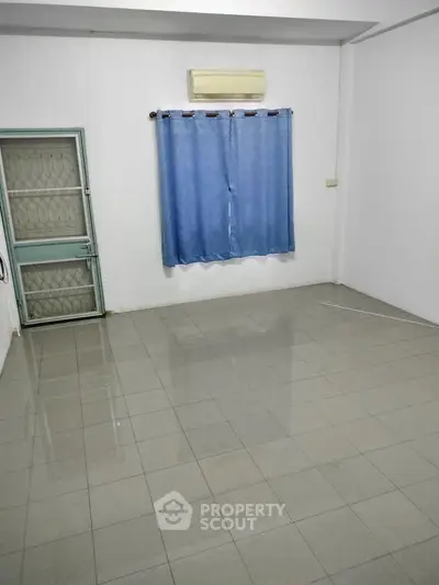 Spacious empty room with tiled floor and blue curtains, ideal for customization.