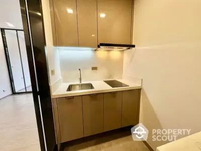 Modern compact kitchen with sleek cabinets and induction cooktop in stylish apartment.