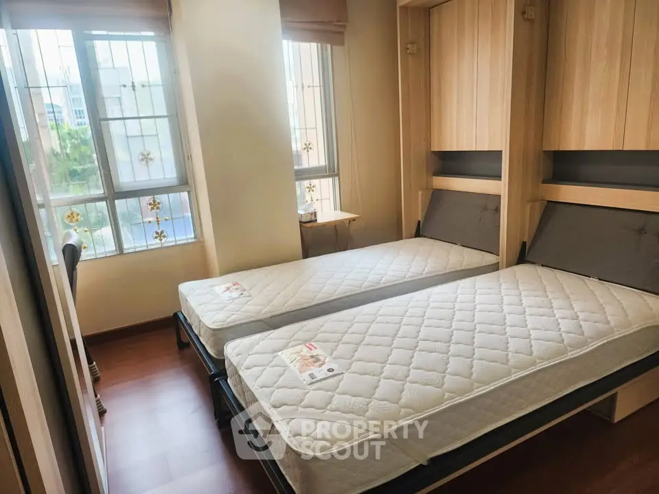 Cozy bedroom with twin beds and large windows offering natural light.