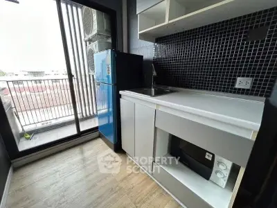 Modern kitchen with sleek cabinetry and balcony access in urban apartment