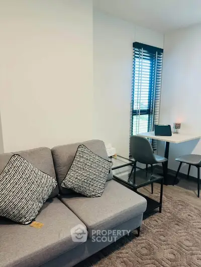 Modern living room with cozy sofa and stylish workspace by the window.