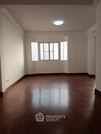 Spacious empty living room with wooden flooring and large window