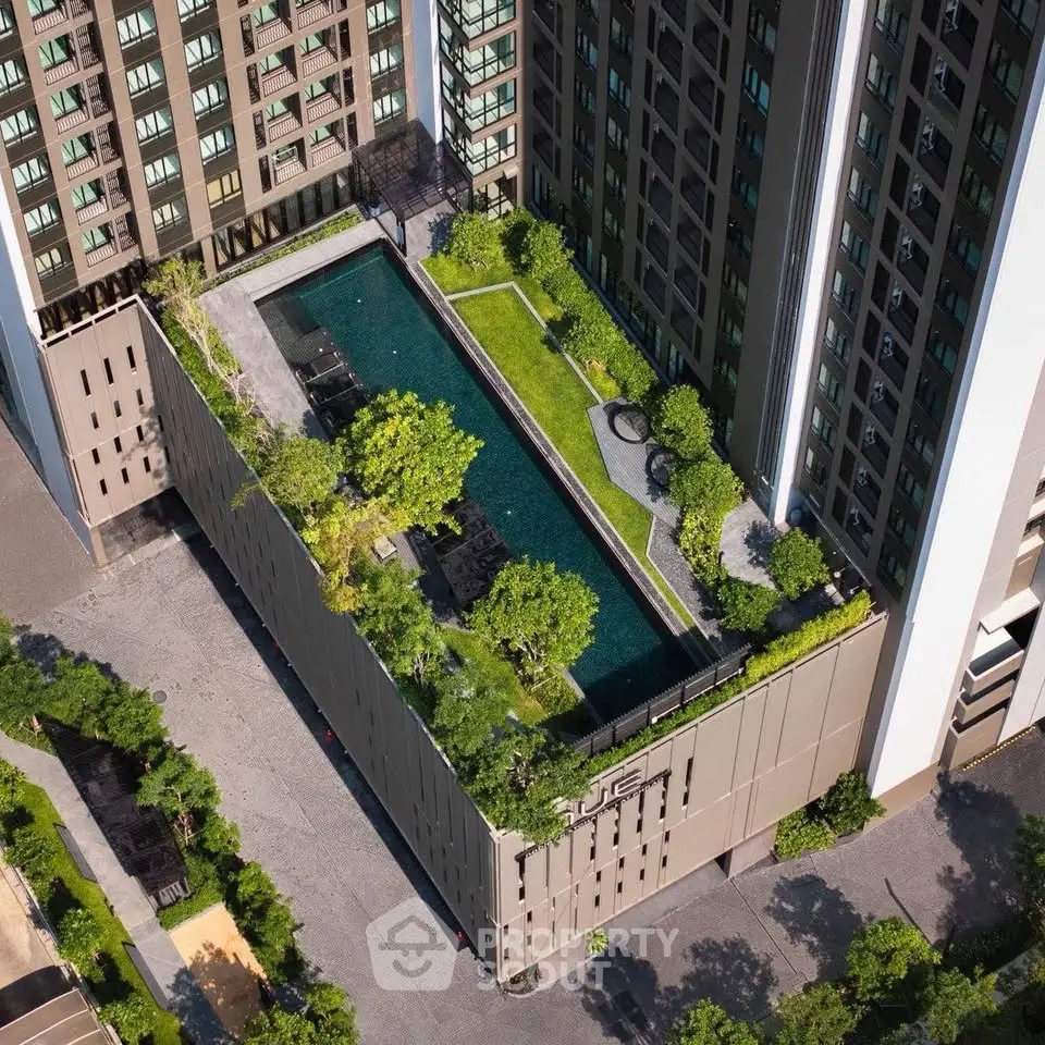 Stunning aerial view of modern building with rooftop pool and lush greenery, perfect for urban living.