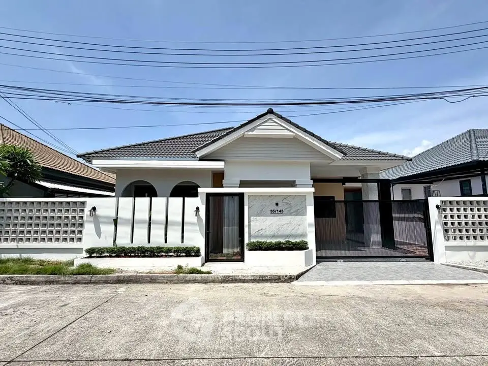 Charming single-story house with modern facade and gated entrance in a serene neighborhood.