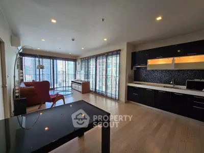 Spacious modern living room with open kitchen and large windows offering natural light and city views.