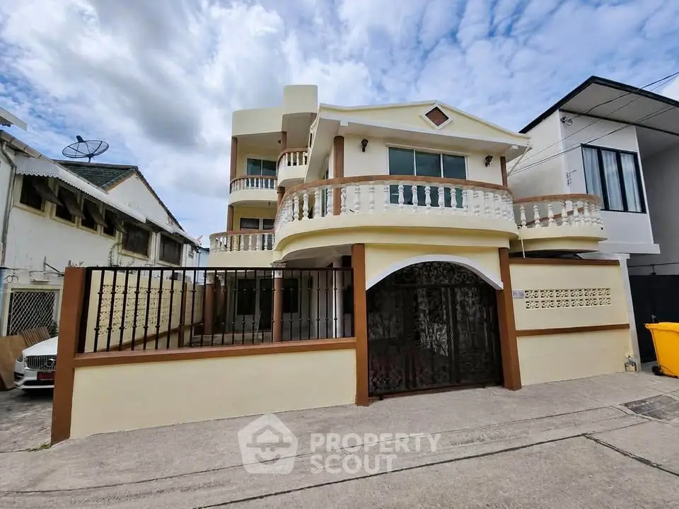 Charming two-story house with unique balcony design and gated entrance in a serene neighborhood.