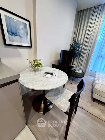 Modern living room with elegant decor and cozy seating area, featuring a stylish round marble table and chic artwork.