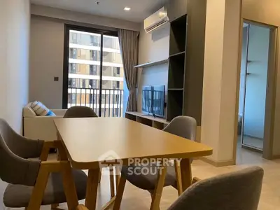 Modern living room with dining area and large window in stylish apartment.