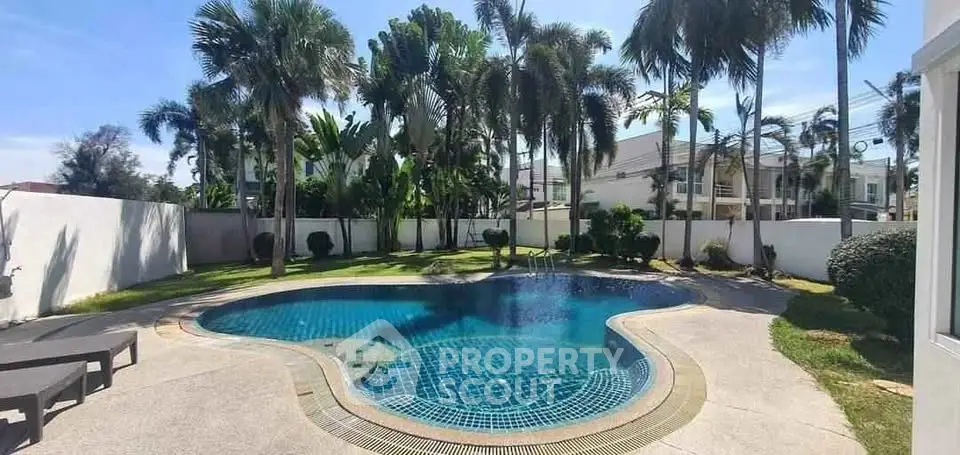 Luxurious private pool surrounded by lush palm trees in a serene residential setting