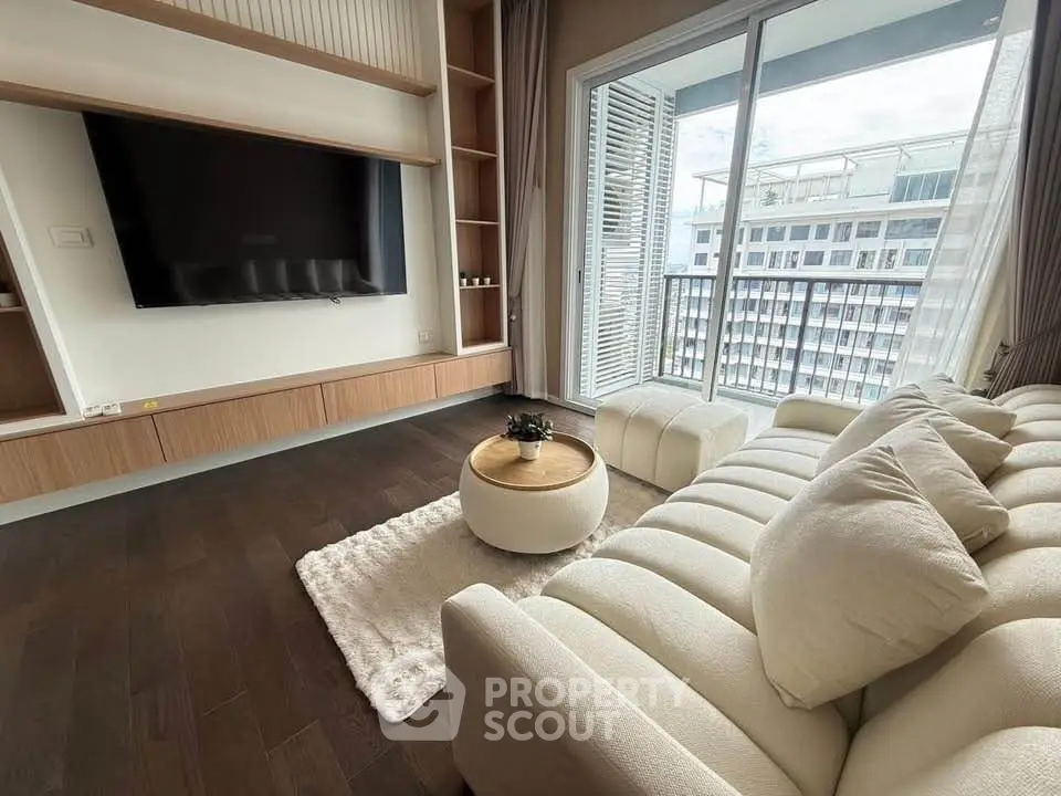 Modern living room with plush sofa, wall-mounted TV, and balcony view in a stylish apartment.