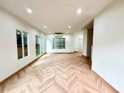 Spacious living room with elegant herringbone flooring and large windows