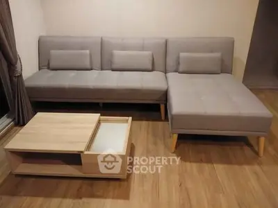 Modern living room with stylish gray sectional sofa and wooden coffee table on hardwood floor.