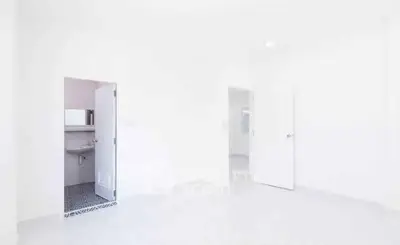 Bright minimalist interior with white walls and open doors, showcasing a sleek bathroom entrance.